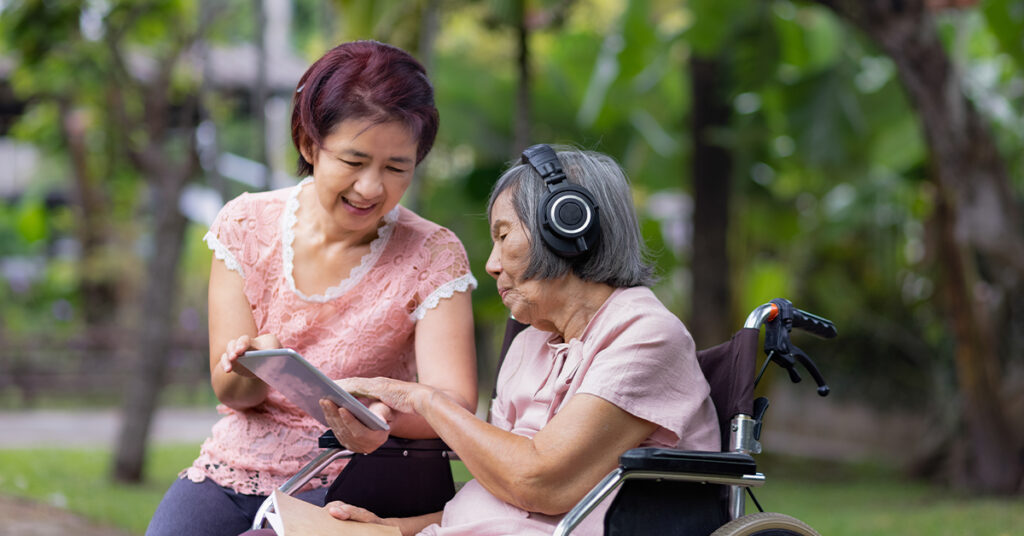 senior woman and daughter listening music with headphone in backyard