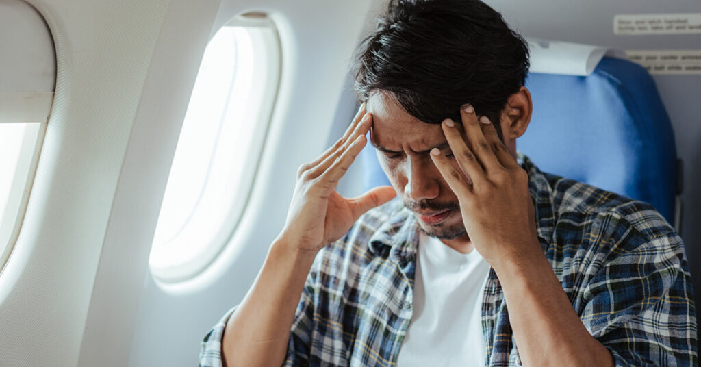 An airplane passenger sits tensed and afraid in his seat